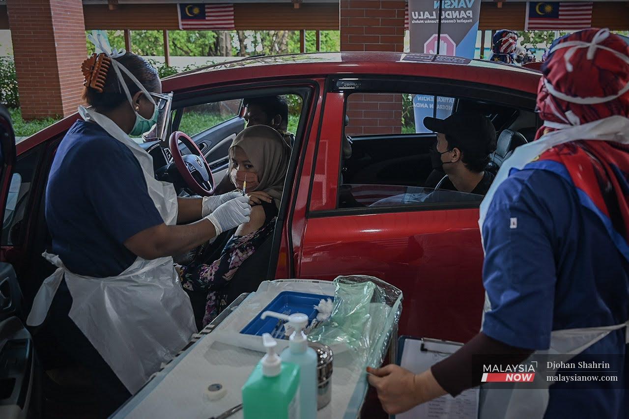 A health worker administers a second dose of Pfizer vaccine at a drive-thru vaccination centre at the Universiti Kebangsaan Malaysia Medical Centre in Cheras.