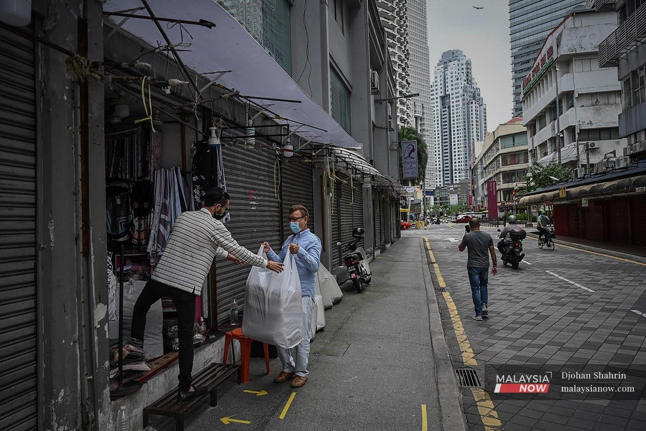 A shopkeeper in Kuala Lumpur brings in new stock as part of preparations to reopen after receiving the green light from Putrajaya to cater to fully vaccinated customers.