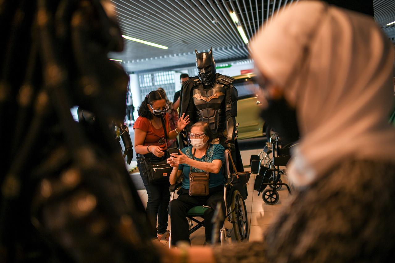 A volunteer dressed up as Batman helps a senior citizen at the vaccination centre at the SPICE Convention Centre in George Town. Photo: Bernama