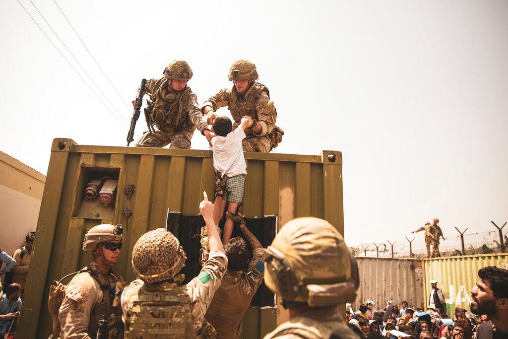 In this image provided by the US Marine Corps, British and Turkish coalition forces, along with US Marines, assist a child during an evacuation at Hamid Karzai International Airport in Kabul, Afghanistan, Aug 20. Photo: AP