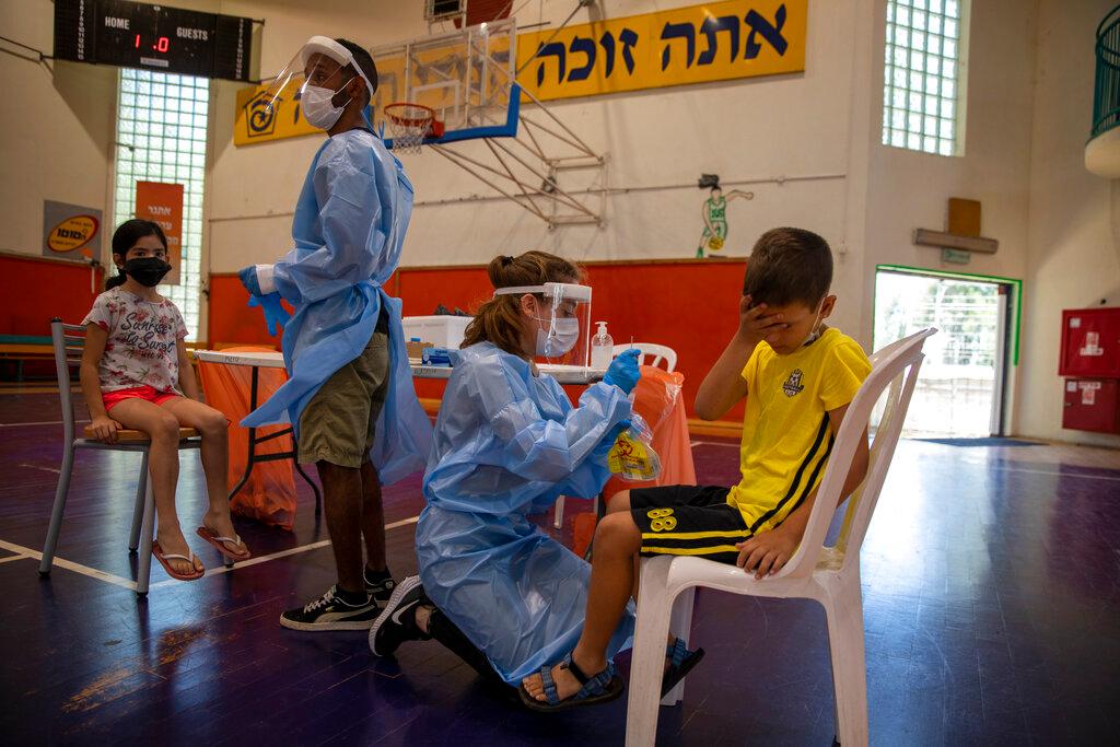 In this June 29 file photo, medical personnel test Israeli children for the coronavirus at a basketball court turned into a testing centre, in Binyamina, Israel. Photo: AP
