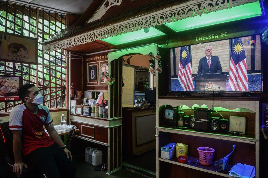 Seorang pekerja restoran menyaksikan Ismail Sabri Yaakob menyampaikan perutusan pertama sebagai perdana menteri. Gambar: Bernama