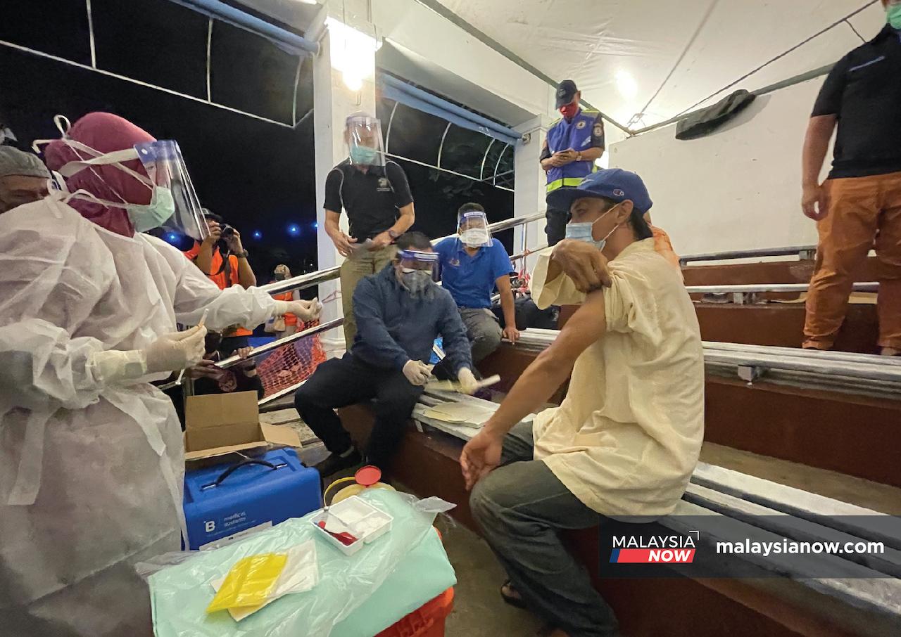 Madzidi Bujang rolls up his sleeve to receive a dose of Covid-19 vaccine in Kuching, Sarawak.