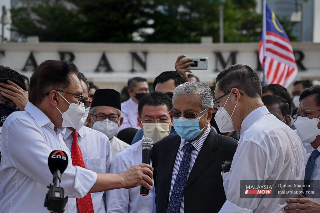 PKR president Anwar Ibrahim hands the microphone to Dr Mahathir Mohamad at a gathering of opposition MPs at Dataran Merdeka on Aug 2 after they were barred from entering the Parliament building due to the detection of Covid-19 cases.