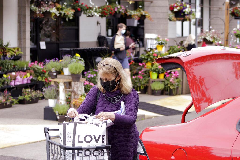 A woman wearing a face mask loads groceries into her car after shopping at a grocery store in Portland, Oregon, May 21. Photo: AP