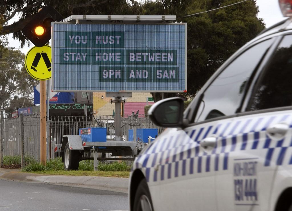 A police car drives past a curfew sign in Melbourne on Aug 25, as the city experiences its sixth lockdown while battling an outbreak of the Delta variant of coronavirus. Photo: AFP