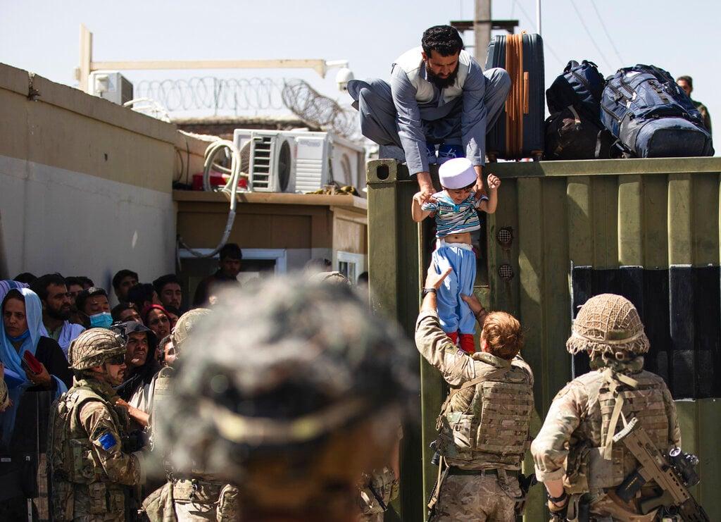 In this image provided by the US Army, an Afghan man hands his child to a British paratrooper at Hamid Karzai International Airport in Kabul, Afghanistan, Aug 26. Photo: AP