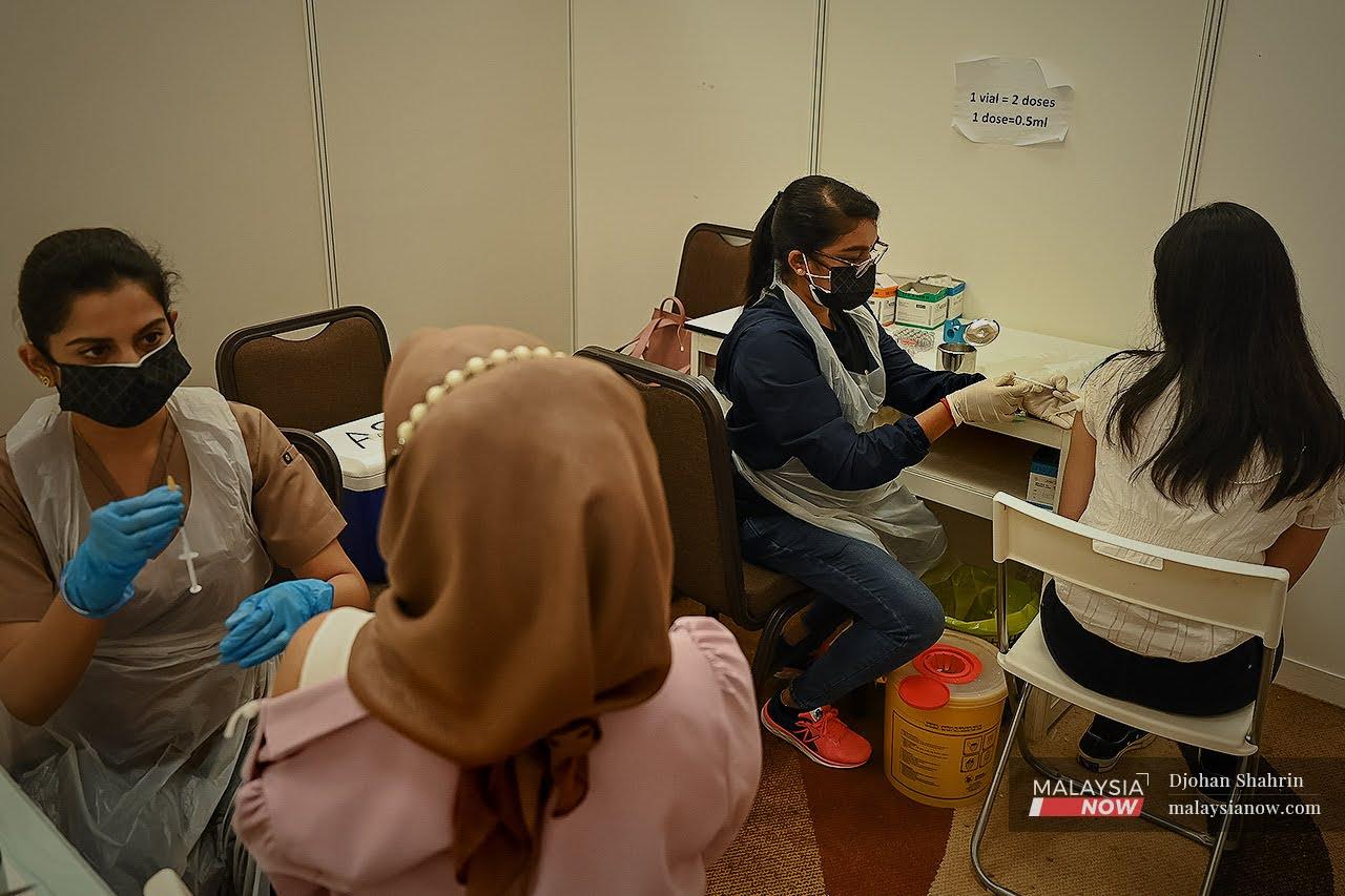Health workers administer doses of Covid-19 vaccine at a vaccination centre in Selangor. Medical experts warn that children are at risk of transmitting the virus from unvaccinated parents or caretakers.