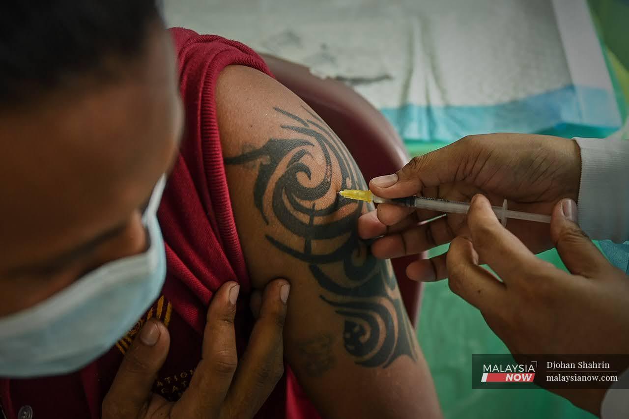 An Orang Asli man from the Temuan tribe shows a tattoo as he receives a second dose of Pfizer vaccine at a mobile vaccination unit in Hulu Langat.