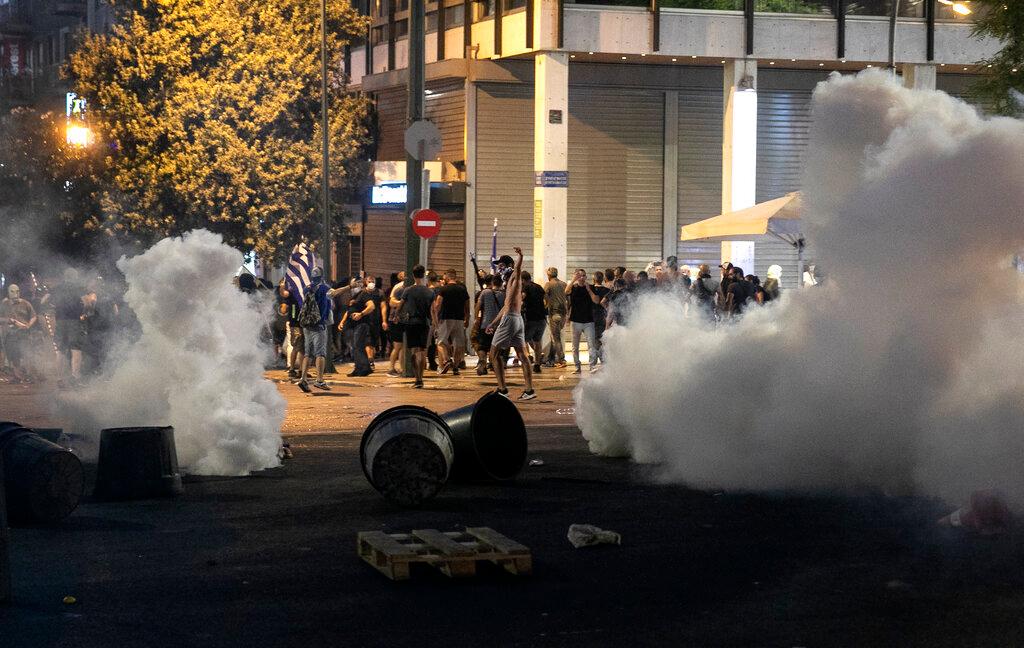 Anti-vaccine protesters run to avoid tear gas during clashes at central Syntagma square, in Athens, Greece, Aug 29. Police used tear gas to disperse thousands of protesters opposing the government's plans for mandatory vaccination and new testing requirements and attendance restrictions on people who aren't vaccinated against Covid-19. Photo: AP