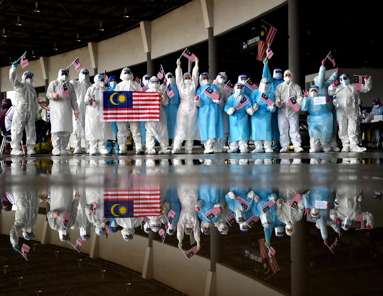 Frontline workers in Pahang wave Malaysian flags during a Covid-19 screening at a drive-thru centre in Kuantan. Photo: Bernama