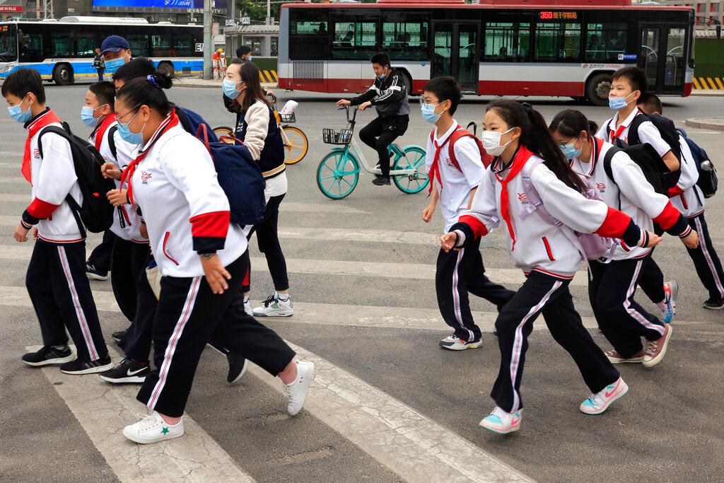 Schoolchildren wearing masks cross a busy traffic intersection in Beijing in this April 29 file photo. Photo: AP