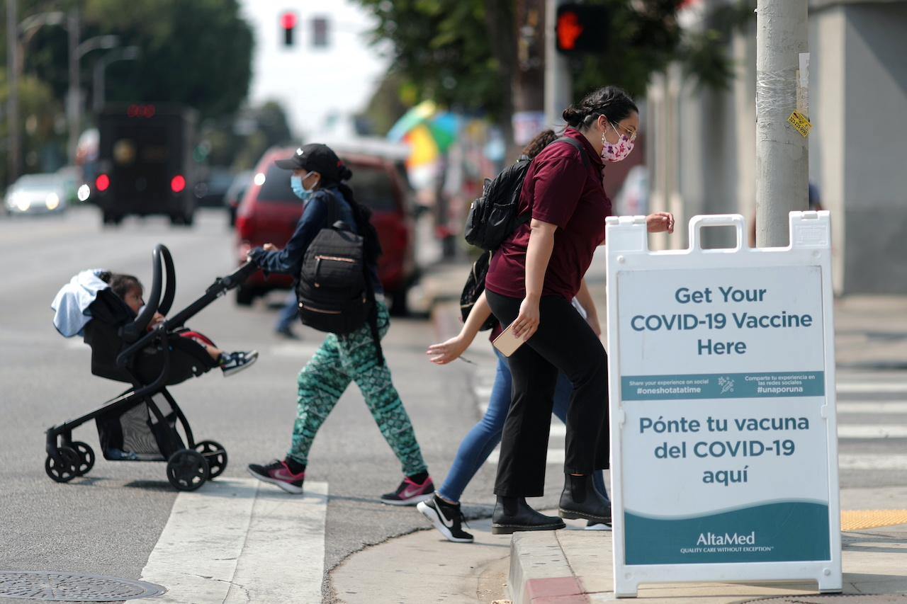 People walk past a sign for a Covid-19 vaccination clinic in Los Angeles, California, Aug 17. Photo: Reuters