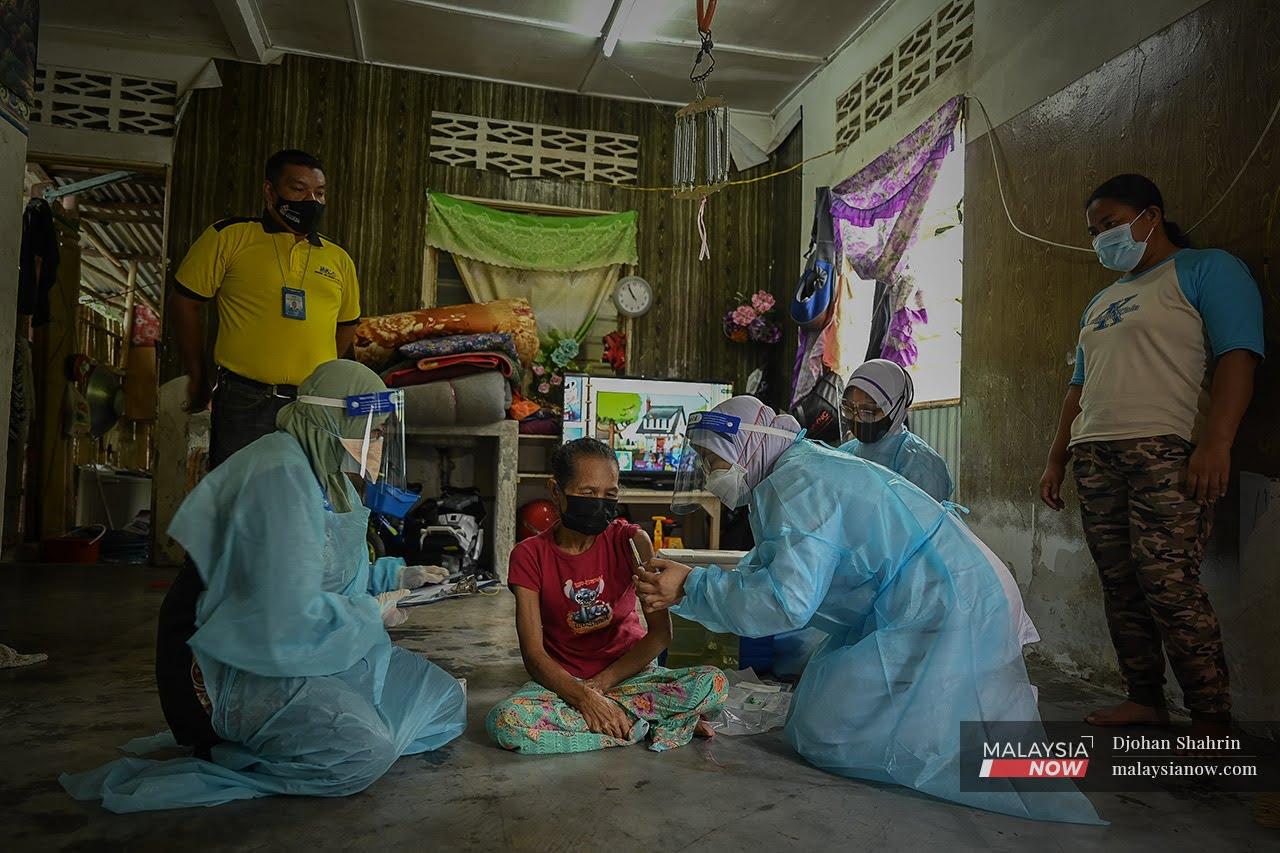 Medical workers administer a jab of Pfizer vaccine to an Orang Asli woman in Hulu Langat, Selangor.