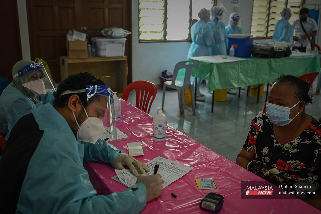 A medical worker takes down the details of an Orang Asli woman before explaining the vaccination process to her at a centre in Sungai Congkak, Hulu Langat in Selangor.