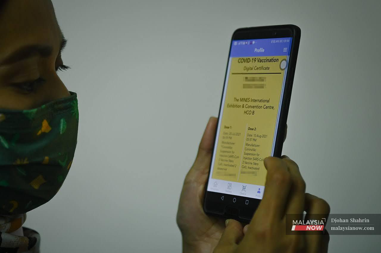 Seorang wanita menyemak sijil digital vaksinasi di dalam aplikasi MySejahtera.