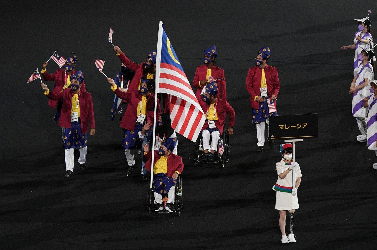 National powerlifting athlete Bonnie Bunyau Gustin with national runner Siti Nooriasah Mohamad Ariffin carry the Jalur Gemilang ahead of the Malaysian contingent at the opening ceremony of the Tokyo 2020 Paralympic Games at the Olympic Stadium on Aug 24. Photo: Bernama