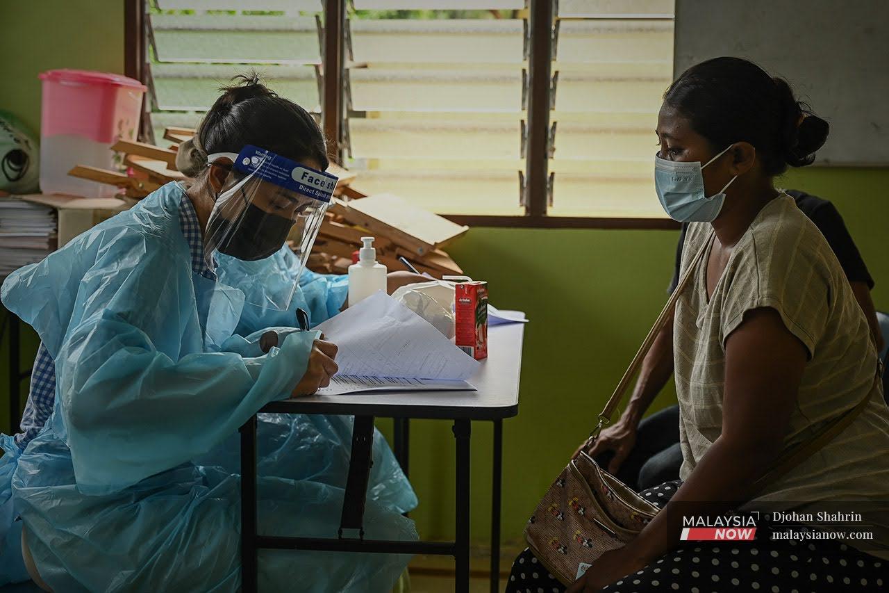 A health worker takes down the details of an Orang Asli woman from the Temuan tribe before administering a shot of Covid-19 vaccine in Kuala Kubu Bharu, Selangor.
