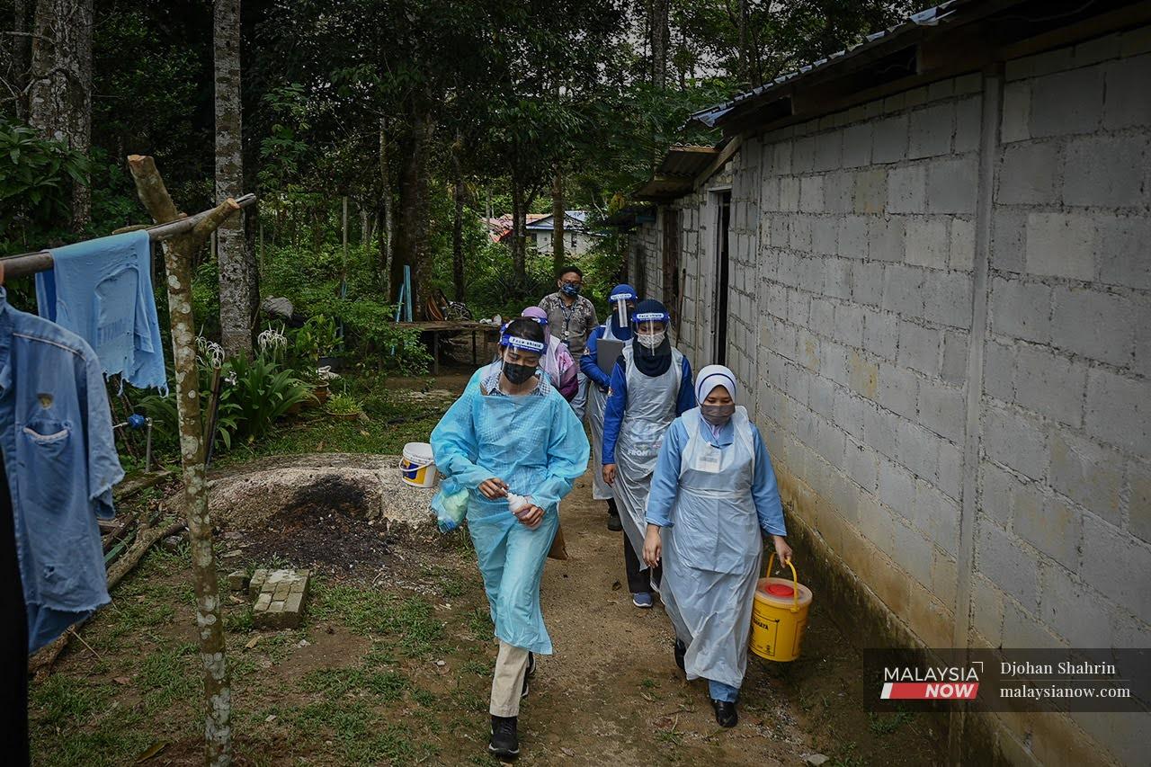 Beberapa petugas kesihatan dari Pejabat Kesihatan Daerah Hulu Selangor berjalan menuju ke beberapa buah rumah Orang Asli Temuan di Kuala Kubu Bharu bagi menerima suntikan pertama vaksinasi.