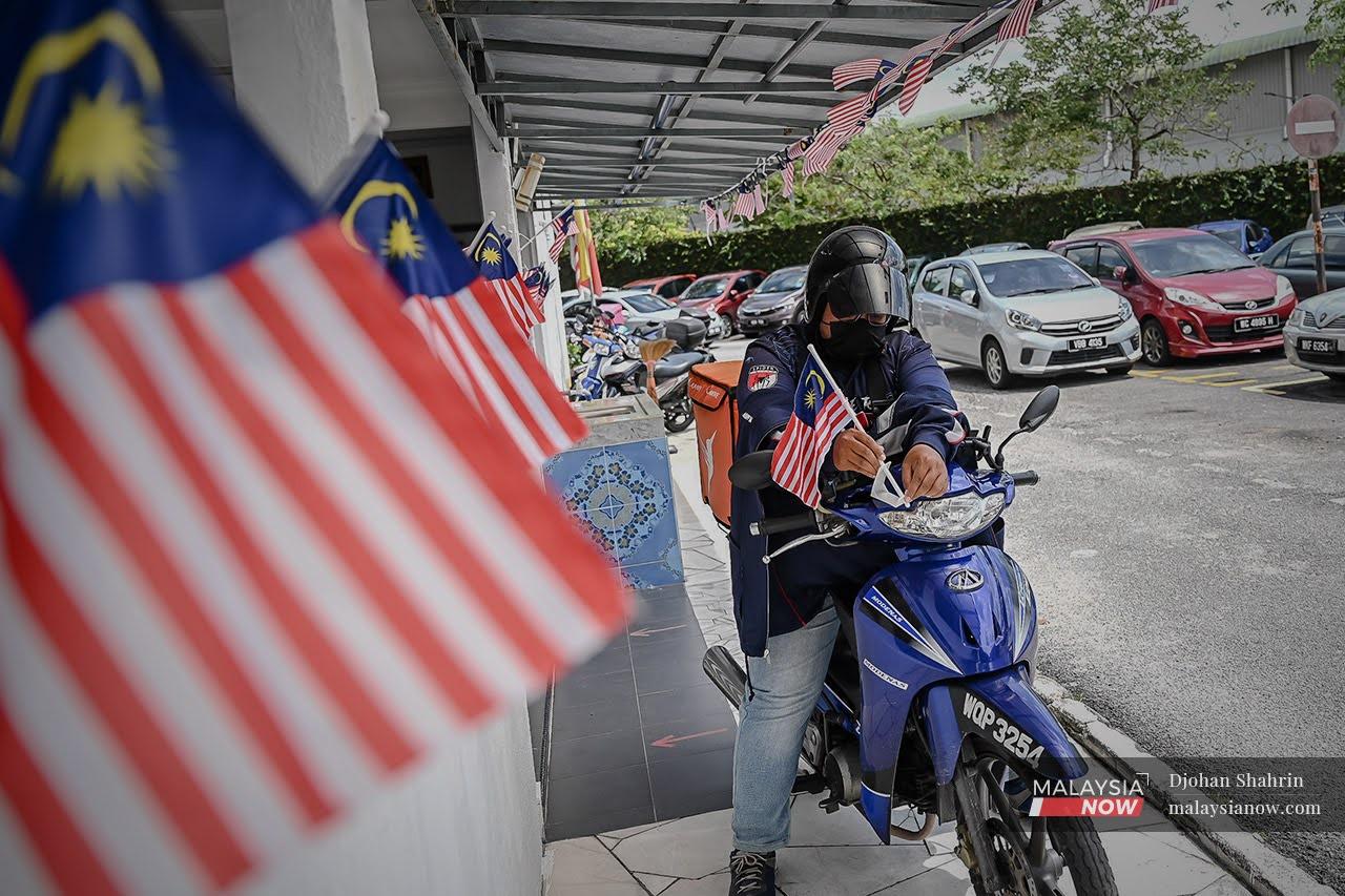 Seorang penunggang motosikal memasang Jalur Gemilang pada motosikal sempena bulan kemerdekaan. Putrajaya melanjutkan moratorium pembaharuan lesen kenderaan sehingga 31 Disember depan.
