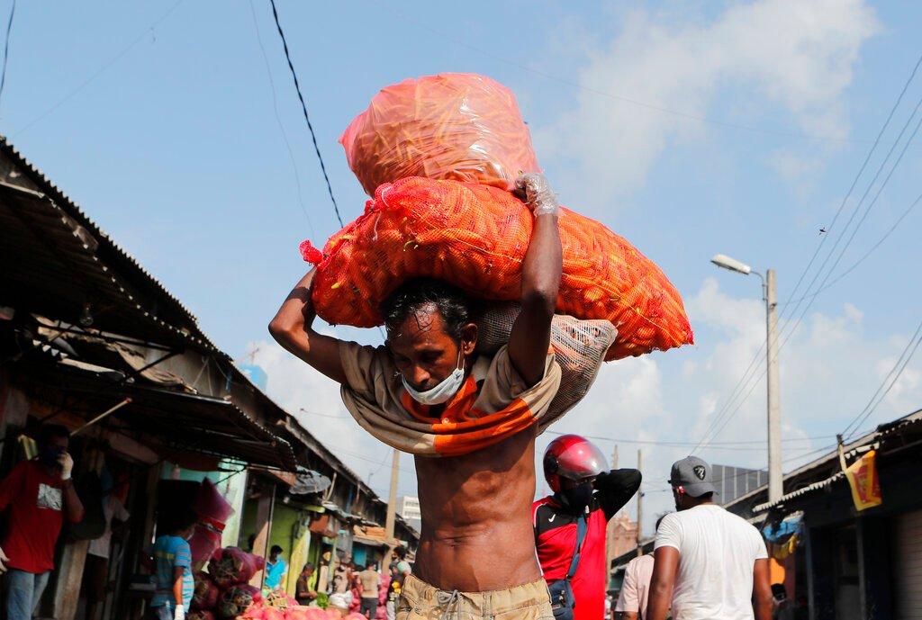 A daily wage labourer carries vegetables at a market place during curfew imposed to stop the spread of the coronavirus in Colombo, Sri Lanka, in this May 1 file photo. Photo: AP