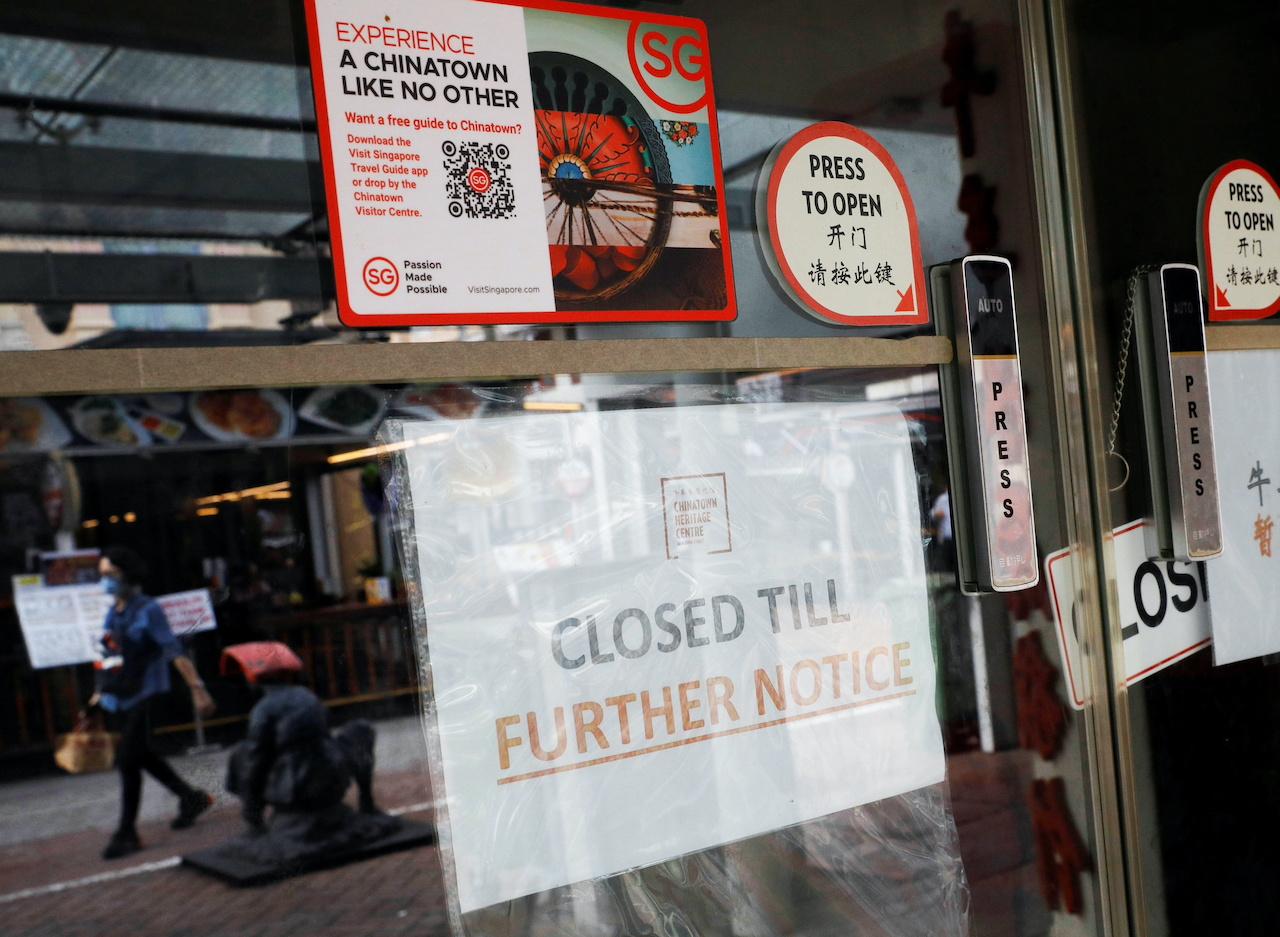 A woman is reflected in the window of a closed shop in Singapore's Chinatown tourist district on Aug 30. Photo: Reuters