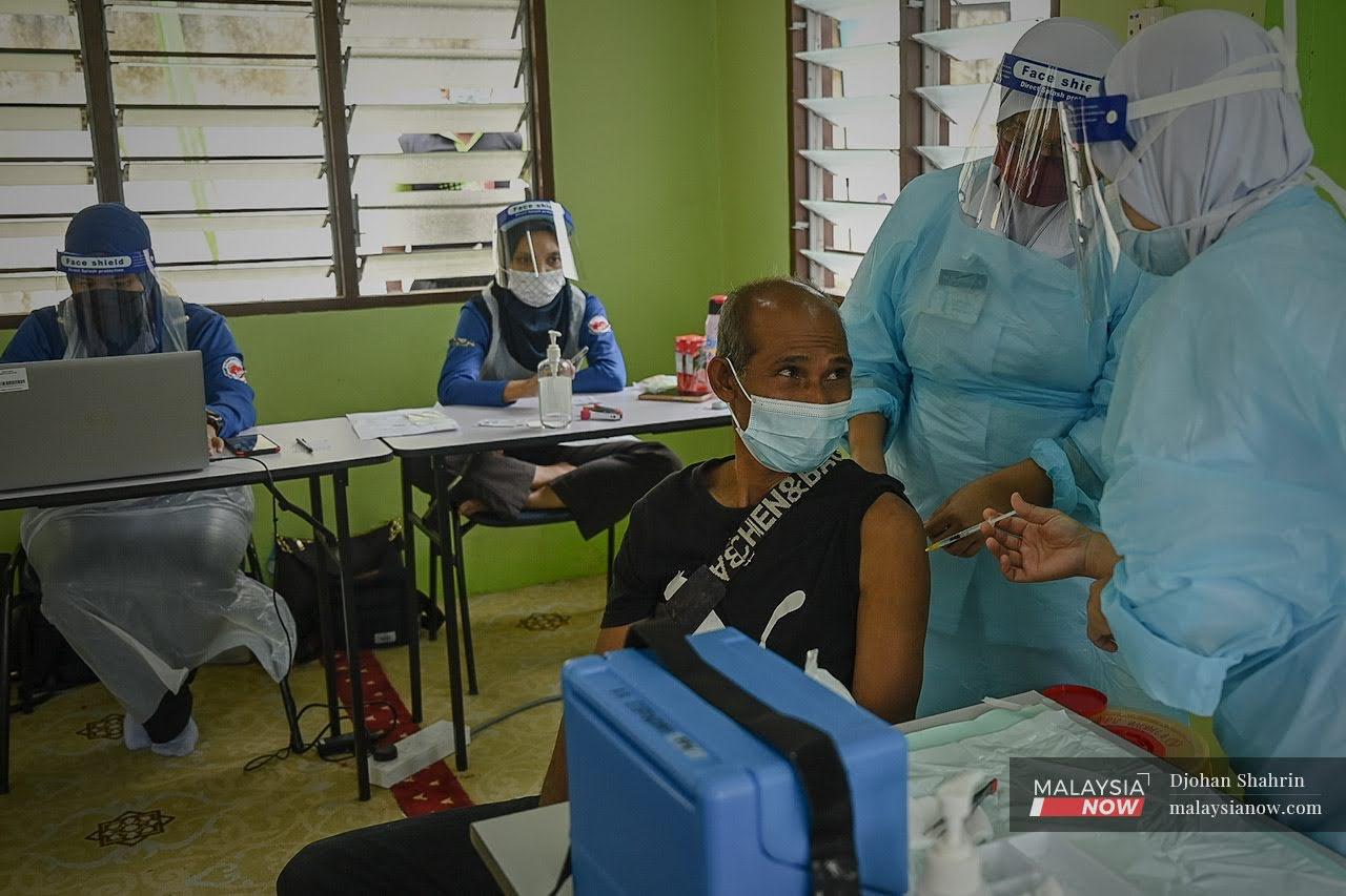 Petugas kesihatan dari Pejabat Kesihatan Daerah Hulu Selangor memberi suntikan vaksin kepada Orang Asli Temuan. Kadar penerima vaksin lengkap kini sudah melebihi 66% populasi negara.
