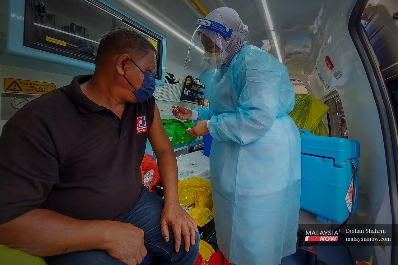 Petugas Kesihatan Hospital Orang Asli Gombak, memberi suntikan vaksin Pfizer Bio-NTech kepada penduduk Orang Asli Temuan di dalam ambulans yang dijadikan pusat vaksin bergerak di Sungai Gabai, Hulu Langat.