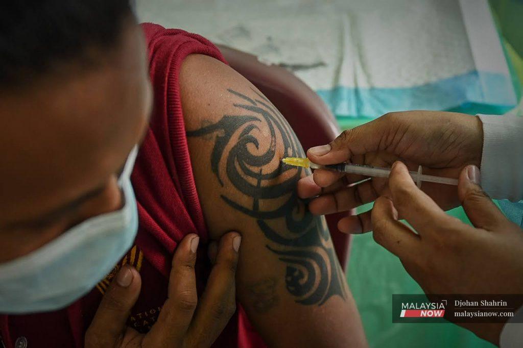 An Orang Asli man from the Temuan tribe shows a tattoo as he receives a second dose of Pfizer vaccine at a mobile vaccination unit in Hulu Langat in this August file picture.