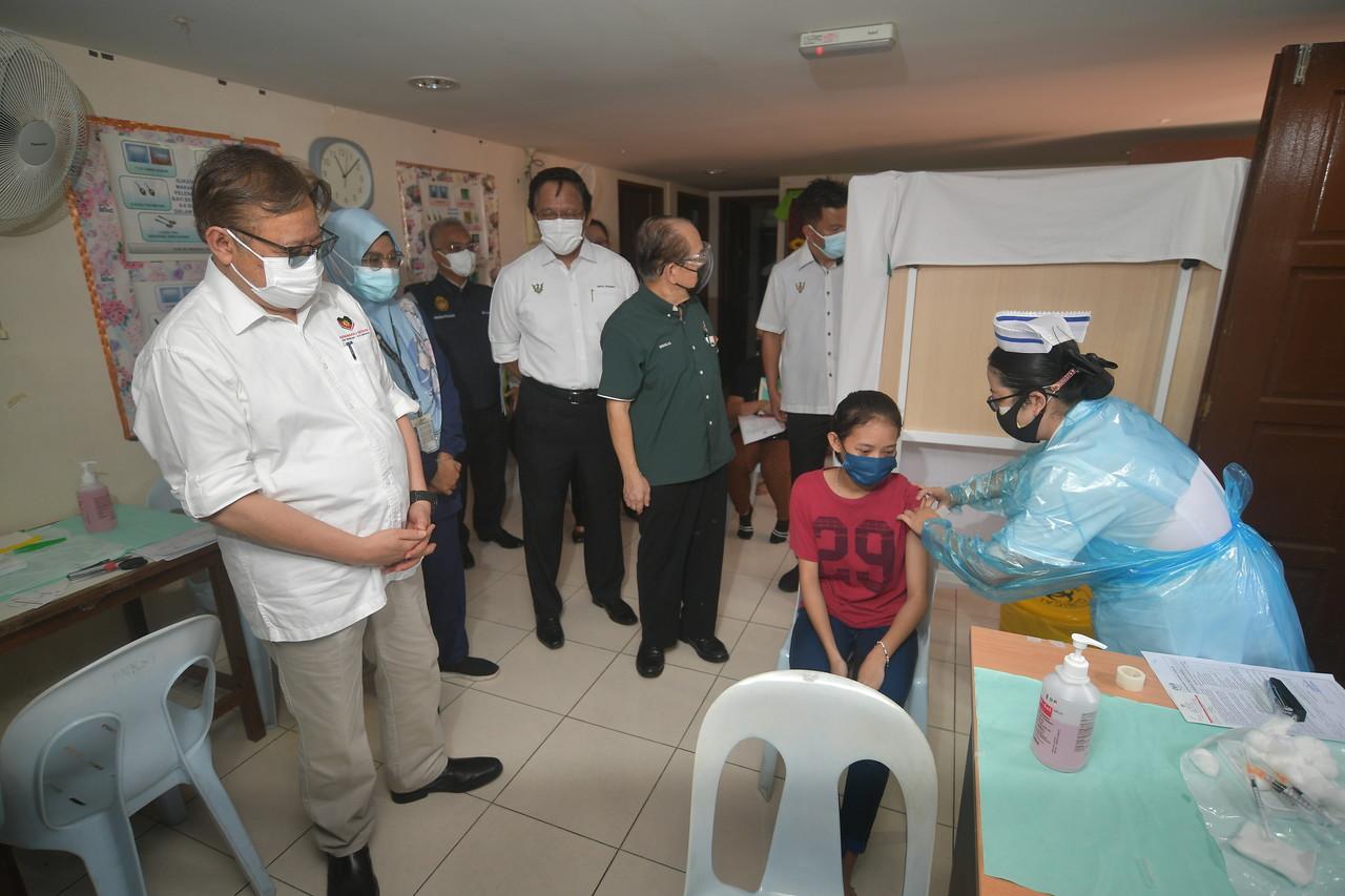 Sarawak Chief Minister Abang Johari Openg (left) watches as a health worker administers a dose of Covid-19 vaccine to a teenager at the Kampung Telaga Air health clinic near Kuching. Photo: Bernama
