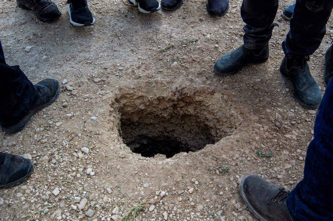 People stand by a hole in the ground outside the walls of Gilboa prison after six Palestinian militants broke out of it in north Israel