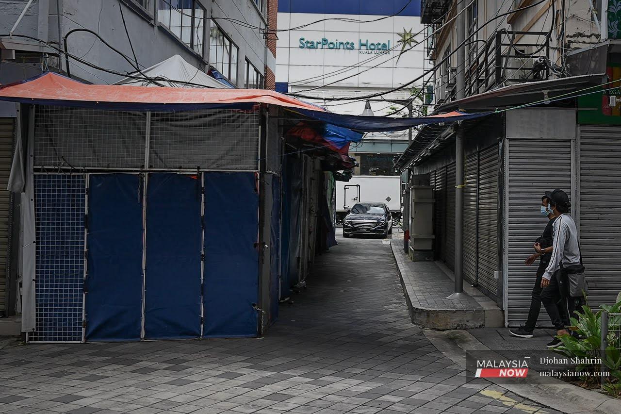 Seorang pejalan kaki berjalan di kawasan deretan kedai yang masih menutup perniagaan mereka di Jalan Tuanku Abdul Rahman.