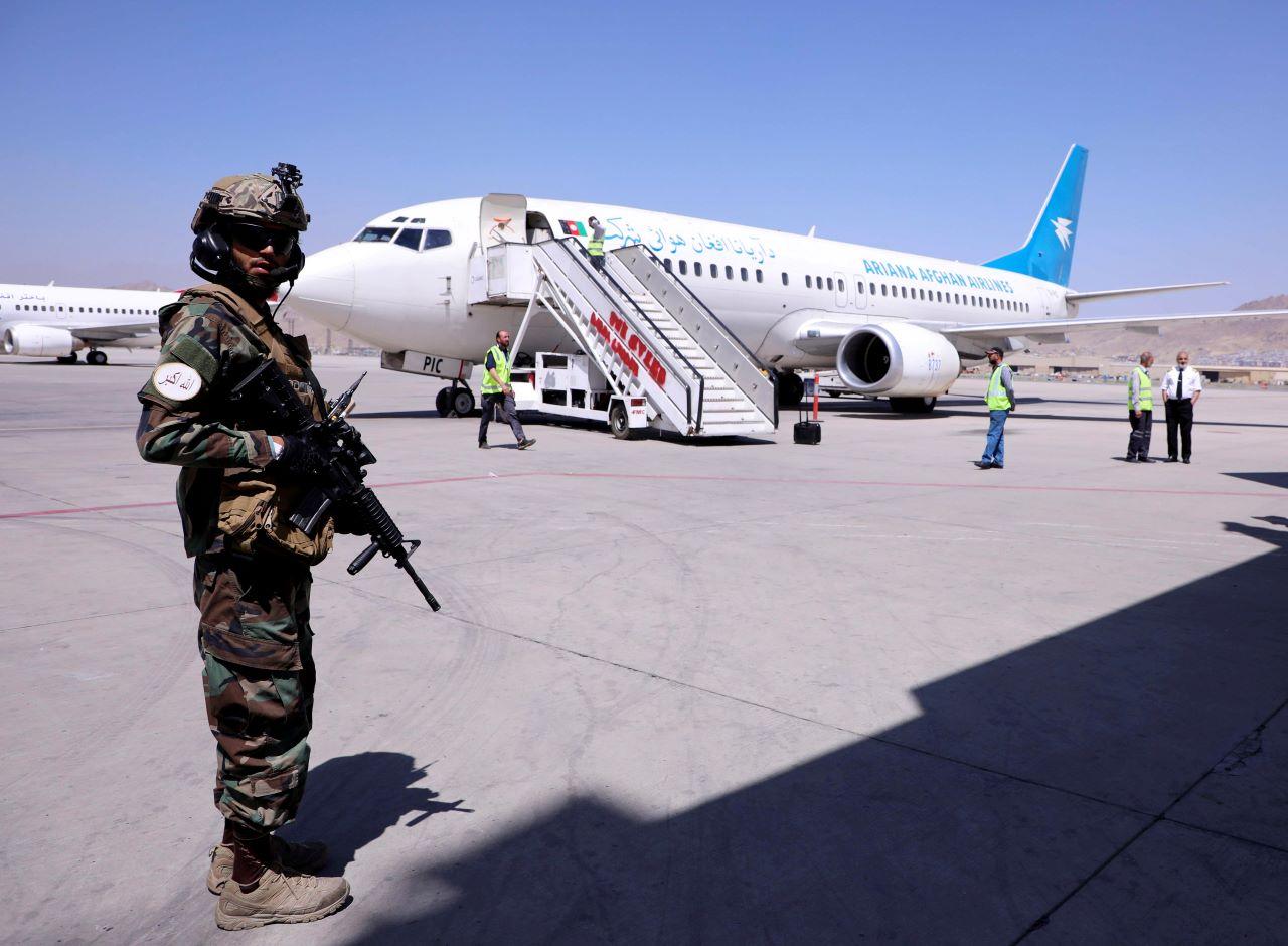 A member of Taliban forces stands guard next to a plane that has arrived from Kandahar at Hamid Karzai International Airport in Kabul, Afghanistan Sept 5. Photo: Reuters