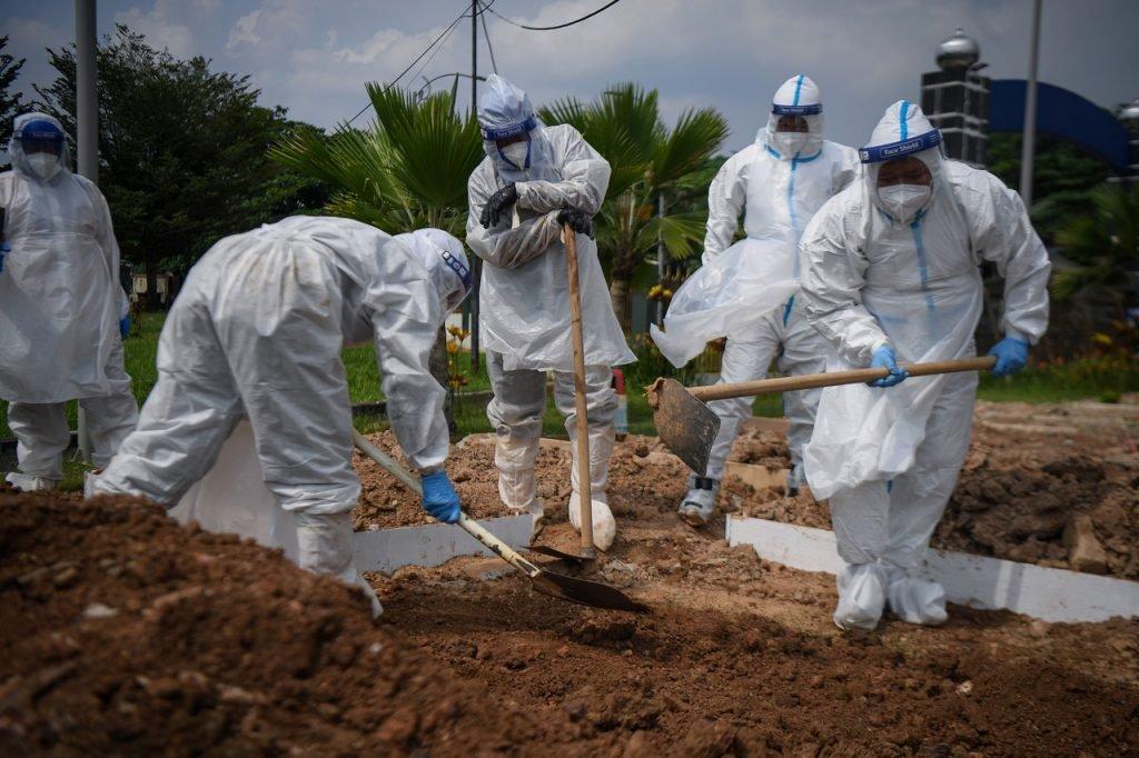 Petugas kesihatan dan anggota pengurusan jenazah memakai PPE lengkap untuk mengebumikan jenazah. Gambar: Bernama