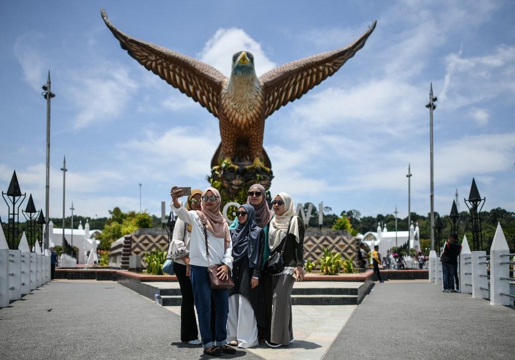Visitors pose for a picture in front of the statue of an eagle, an iconic landmark of Langkawi, in this file photo taken on April 15, 2018, before the arrival of the Covid-19 pandemic. Photo: AFP