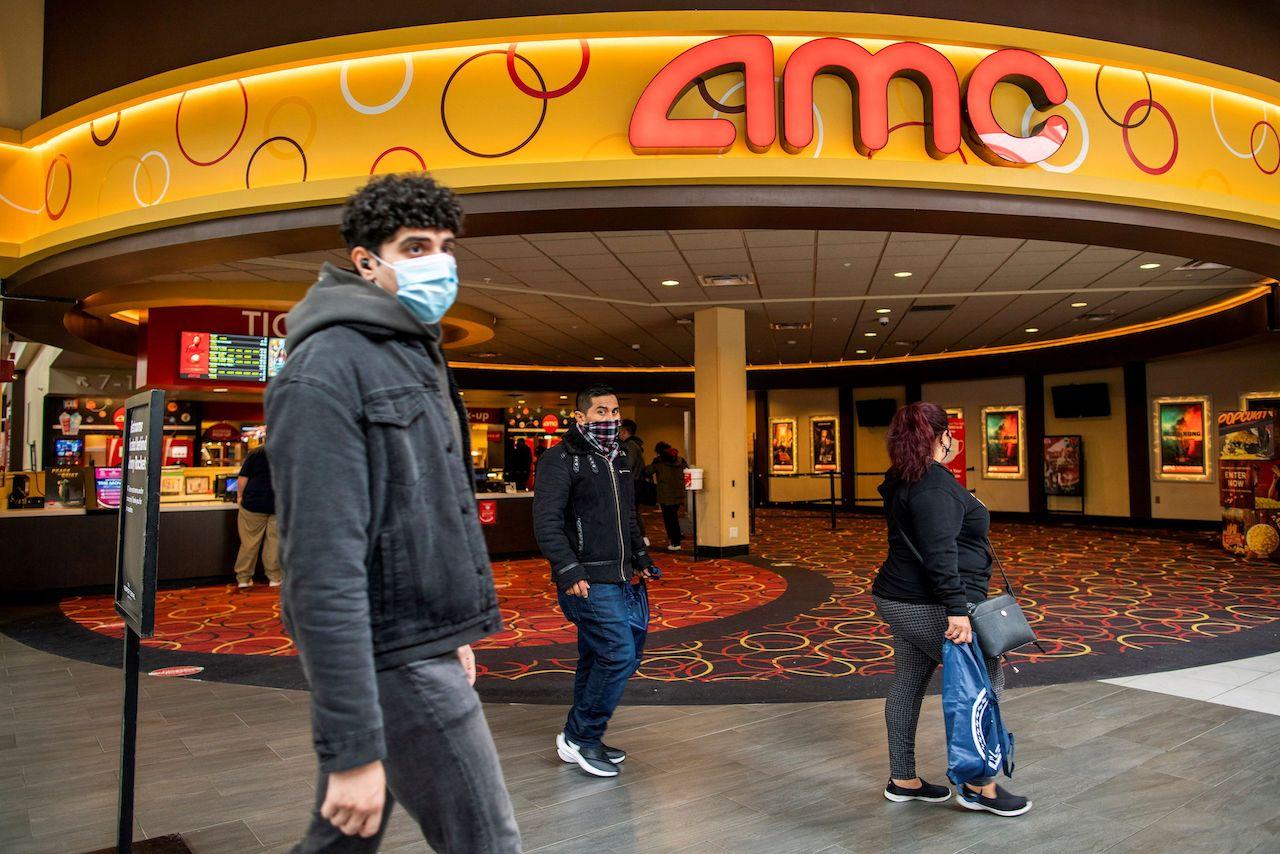 FILE PHOTO: People wear face masks as they walk by a movie theater during the coronavirus disease (COVID-19) pandemic in Newport, New Jersey