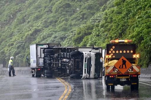 A policeman walks toward an overturned vehicle in New Taipei City as typhoon Chanthu approaches on Sept 12. Photo: AFP