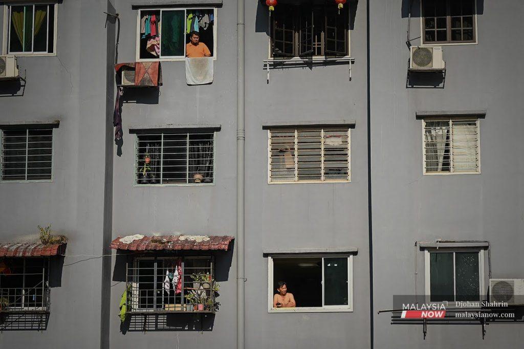 Residents look out of their windows at an apartment block in Cheras which was placed under total lockdown in May.
