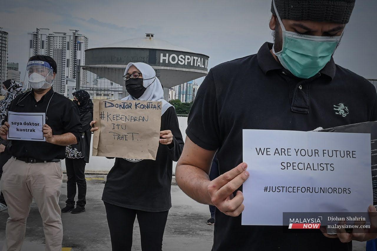 Contract doctors hold up placards during a peaceful demonstration at Hospital Kuala Lumpur on July 26.