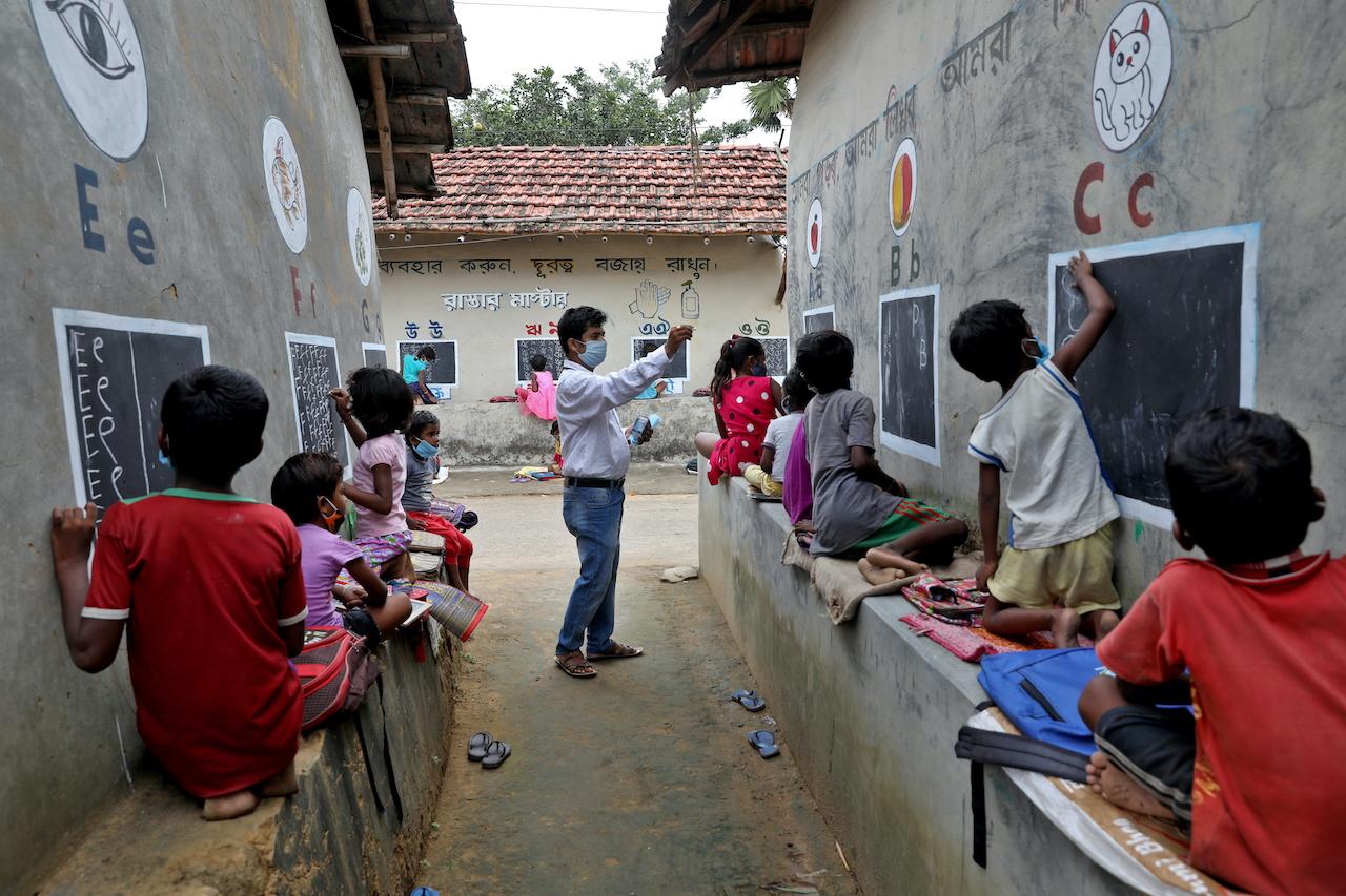 A teacher conducts a class in the open air outside houses whose walls have been converted into blackboards for students who do not have access to the internet or gadgets following the closure of schools due to the Covid-19 pandemic in West Bengal, India, Sept 13. Photo: Reuters