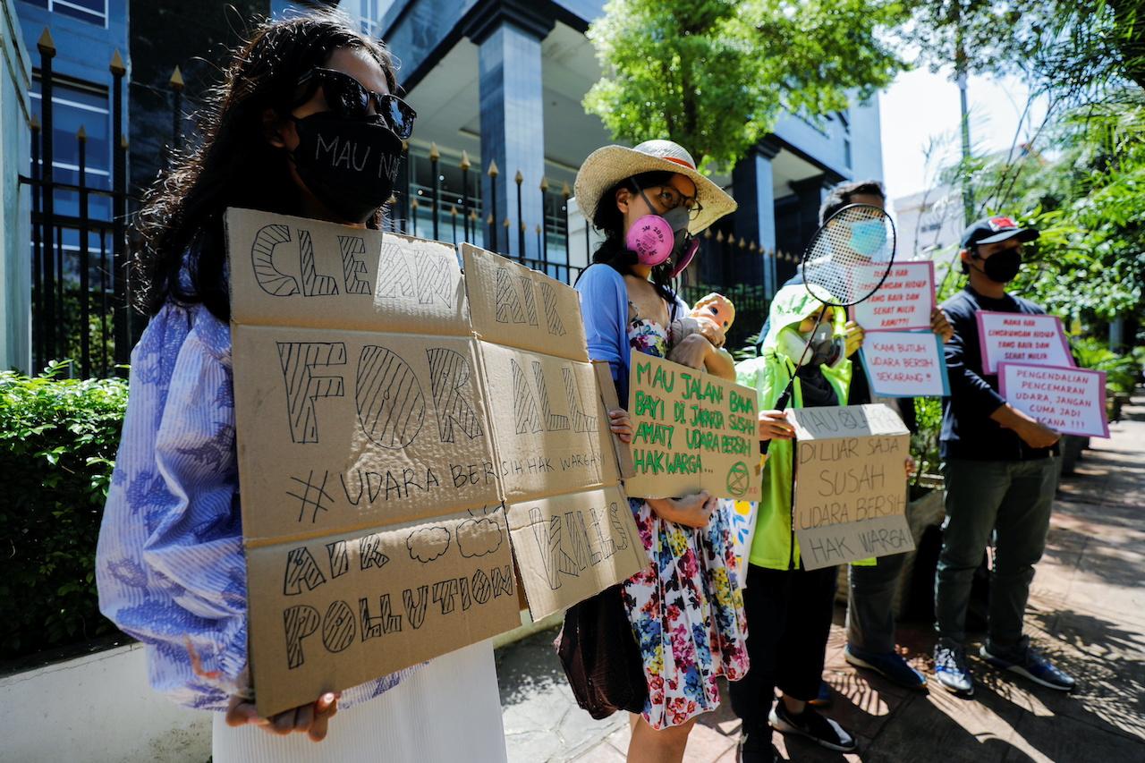 Environmental activists wearing protective masks hold placards outside the Central Jakarta Court following the hearing of a citizen lawsuit, done in an attempt to sue the government into taking action on the city's chronic levels of air pollution, in Jakarta, Indonesia, Sept 16. Photo: Reuters