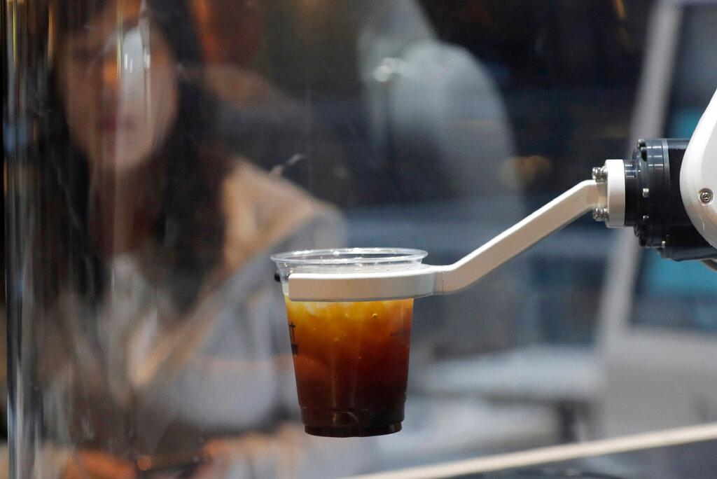 In this May 22, 2019, file photo, a customer waits for a cup of coffee in front of a robot after placing an order at a cafe in Seoul, South Korea. South Korea has a rapidly ageing workforce and is among the world’s fastest adopters of robots. Photo: AP