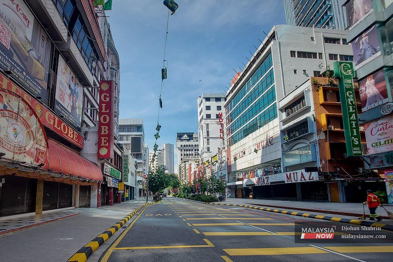 A cleaner sweeps a deserted road along a row of closed shops at Jalan Tuanku Abdul Rahman in Kuala Lumpur during the lockdown in June this year. Many businesses have been battered by the various lockdowns imposed since early last year which by and large saw only essential services allowed to operate.