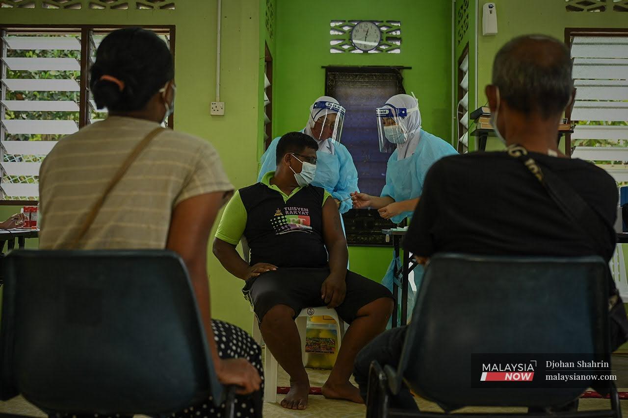 Orang Asli menerima vaksin Covid-19 di pusat pemberian vaksin di Hulu Selangor.