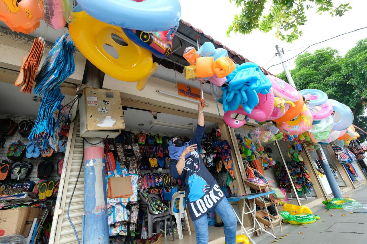 A shopkeeper hangs her goods out at her stall in Pantai Cenang, Langkawi, which reopened to domestic tourists last week. Photo: Bernama