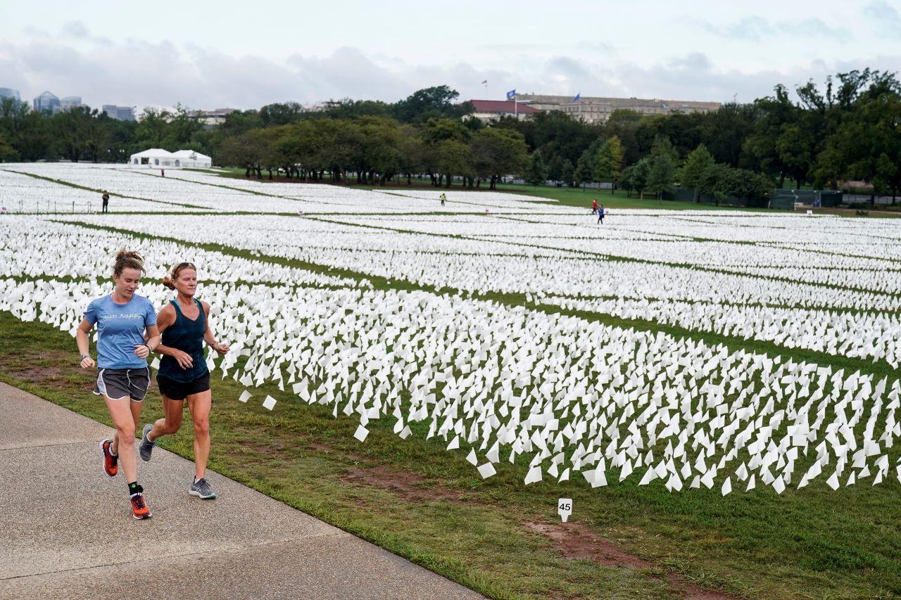 Women run past an exhibition of white flags representing Americans who have died from Covid-19, placed over 20 acres of the National Mall, in Washington, US, Sept 17. Photo: Reuters