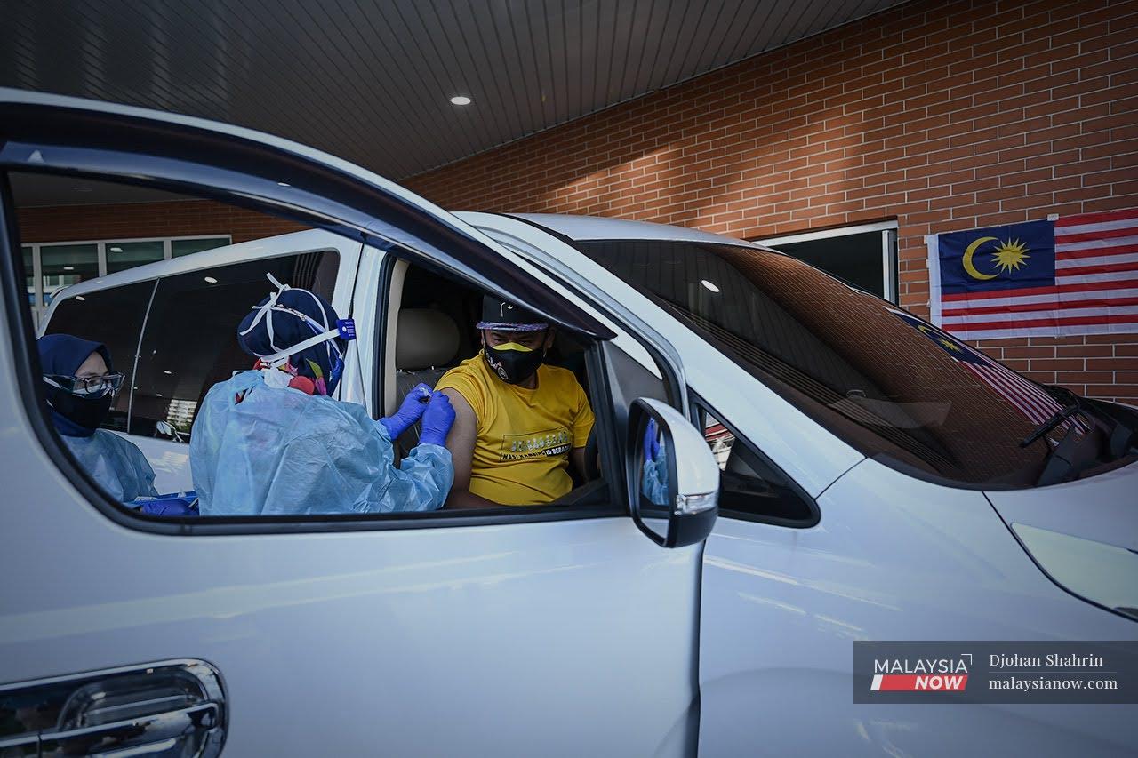 Health workers administer a dose of Covid-19 vaccine at a drive-thru vaccination centre in Cheras.