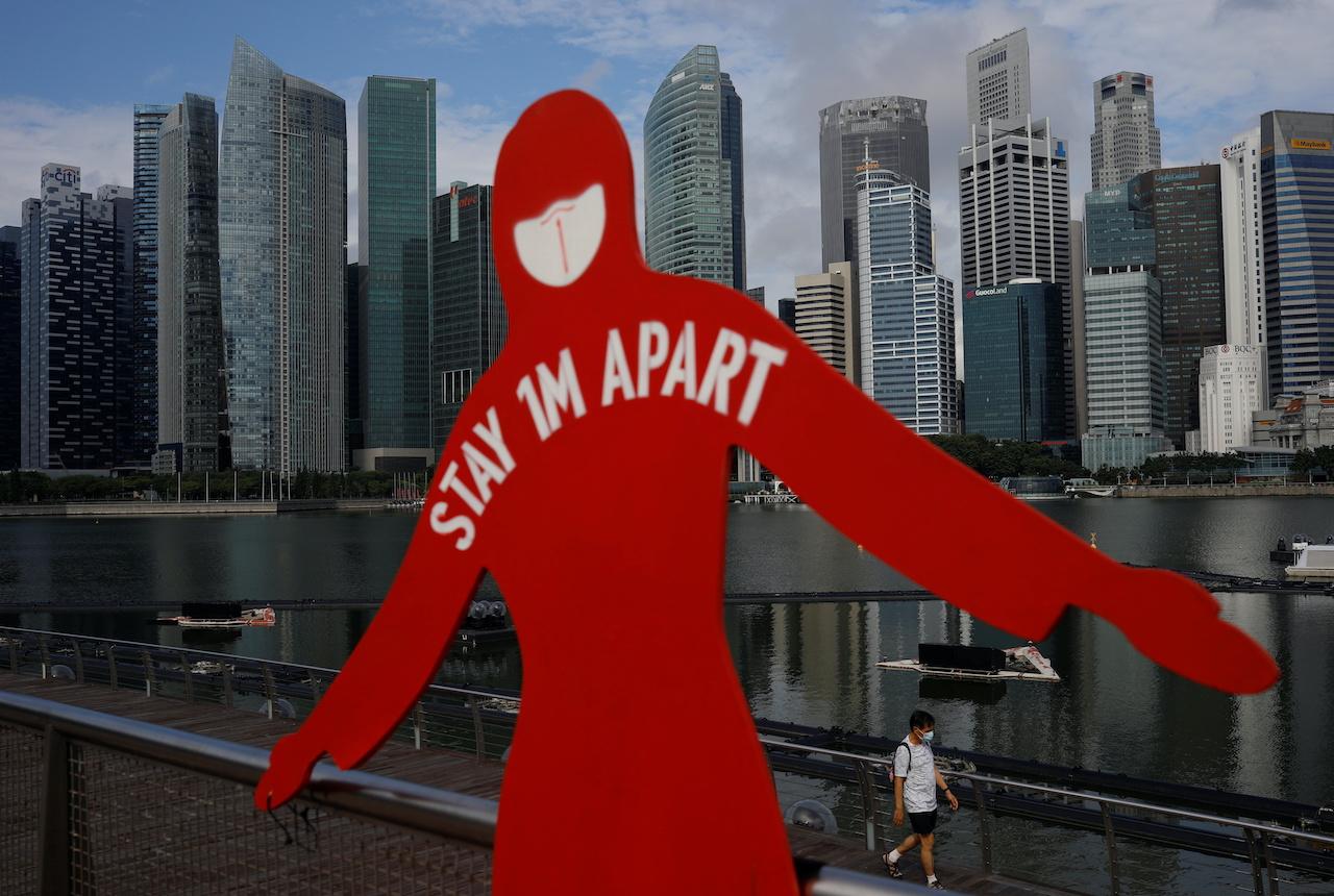 A man wearing a face mask passes a sign put up to encourage social distancing at Marina Bay in Singapore, Sept 22. Photo: Reuters