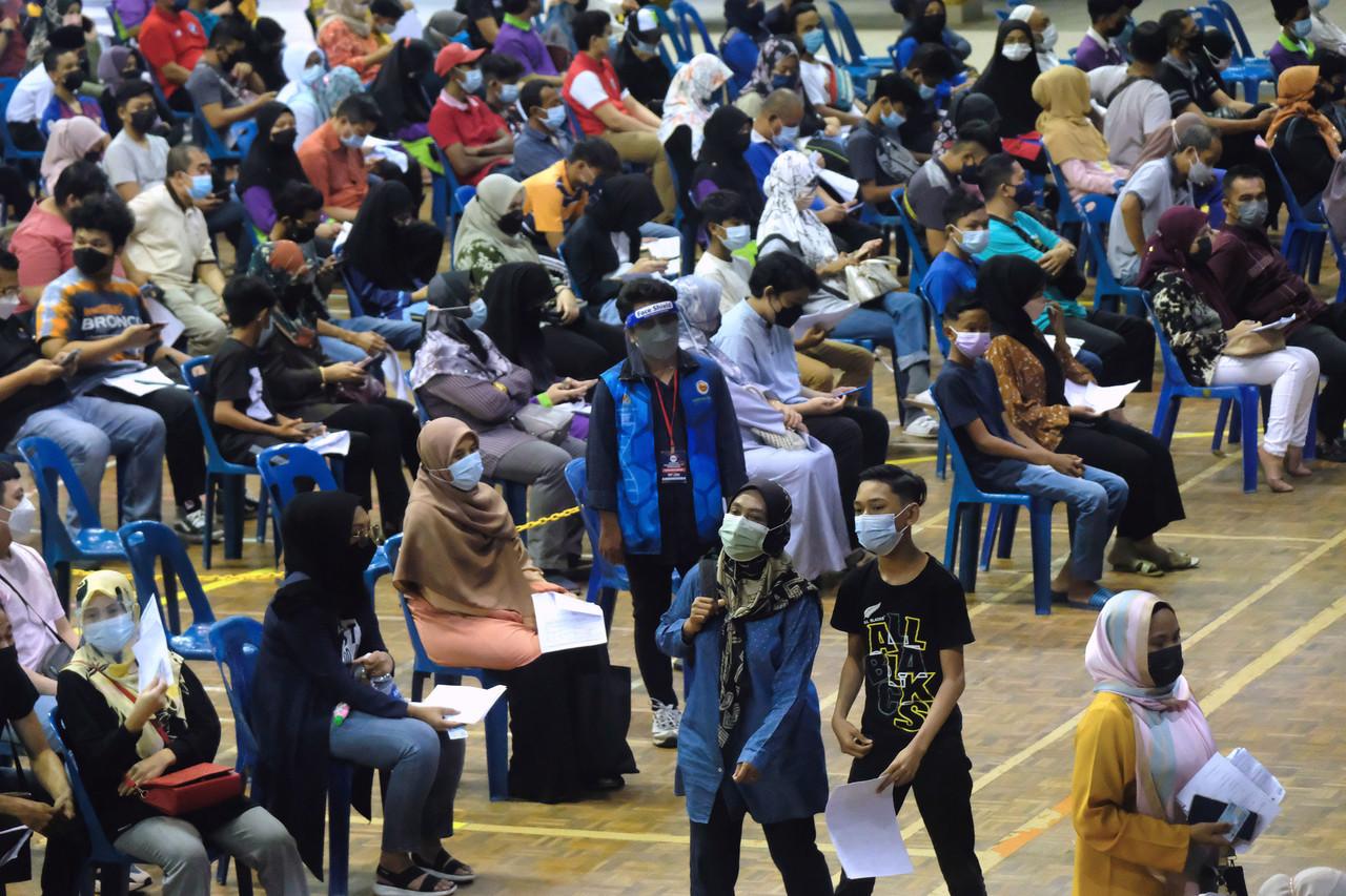 Teenagers wait with their parents to receive their Covid-19 jabs at a vaccination centre in Alor Setar. Photo: Bernama