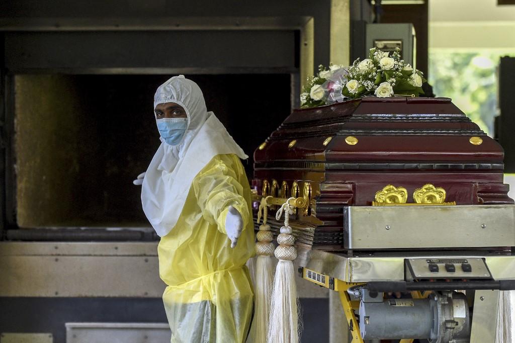 A cemetery worker wearing personal protective equipment prepares to place the coffin of Eliyantha White, a local shaman who claimed he had super natural powers to end the pandemic and died of the Covid-19 coronavirus, inside the furnace at the crematorium of the Colombo General Cemetery on Sept 23. Photo: AFP